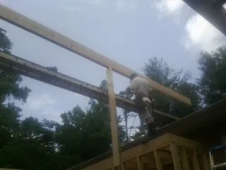 Carpenter setting a ridge beam over a new addition frame — Ice Dam Removal by Roofing Brothers in Wildomar