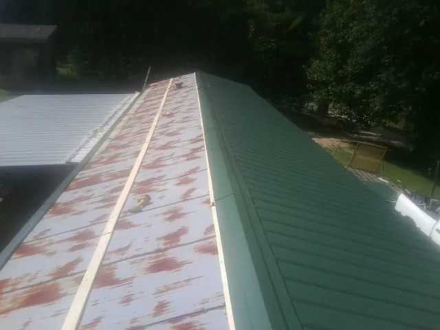 Old rusted panels beside newly installed green metal roofing — Wind Damage Roof Repair by Roofing Brothers in Wildomar