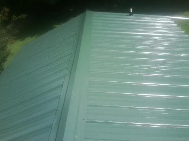 New green metal panels meeting at the ridge of a roof — Flat Roof Repair work by our crew in Wildomar