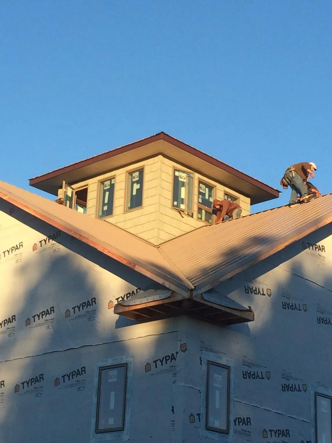 Roofers working around a rooftop cupola on a new metal roof at sunset — Roof Waterproofing in Wildomar by Roofing Brothers